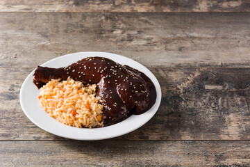 Traditional mole Poblano with rice in plate on wooden table. Copy space