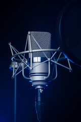 Close-up of a Neumann TLM 102 studio recording microphone in the dark with a spotlight on it