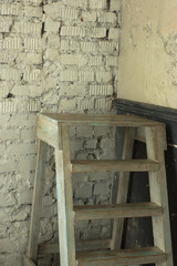 A wooden white staircase a ladder stands in the room