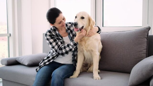 Happy woman petting lovely dog in light apartment