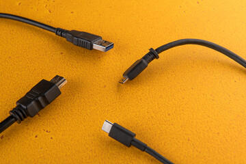 different wires from the computer (hdmi) and phone (usb type c) are on the orange table