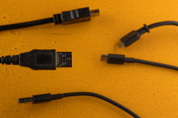 usb computer wire against the background of different wires from a computer and phone are on an orange table