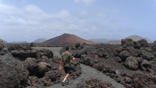 Hombre joven atraviesa el sendero de "Los Hervideros". Al fondo se ve la "Monta&ntilde;a Bermeja". Parque Nacional de Timanfaya. Lanzarote. Islas Canarias