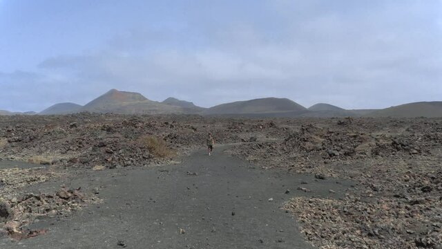 Hombre joven camina por el mar de lavas del Parque Nacional de Timanfaya (Lanzarote) Islas Canarias.