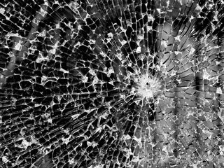 The texture of broken glass on a dark background. The surface is cracked. Broken through. Bullet hole.