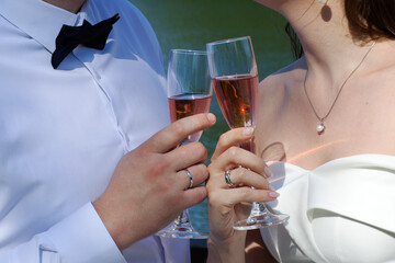 Lovers drink pink champagne from glasses in nature. Wedding. Holiday. 