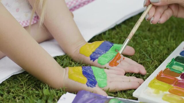 Paint your hands with bright colors. Paints on the body. Palms of the child are painted with bright colors