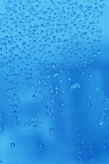 Blue background with droplets on a transparent surface.