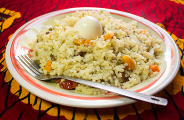 A plate of Nigerian fried rice containing sliced carrots, green beans and pepper, served with a...