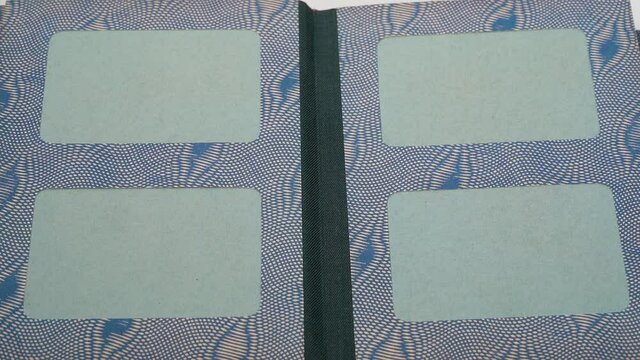 Closeup point of view video of woman turning pages of old vintage cardboard paper photo album with empty green spaces for pictures.
