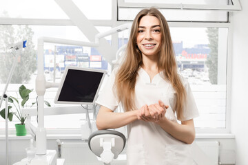 Portrait of female dentist. She standing at her office and she has beautiful smile.