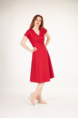 Smiling redhead girl on white background red dress