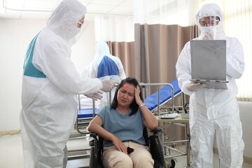 Doctors  in full protective gear collects a sample from a mature woman sitting wheelchair as part of the operations of a coronavirus mobile testing unit.