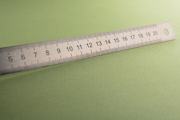 fragment close-up an iron school ruler 20 centimeters long lies on a table; green background