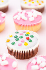 Colorful cupcakes on a pink background.