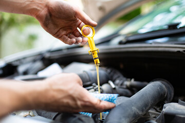 Checking car engine oil level with dipstick, under the hood of a car. Vehicle check-up.