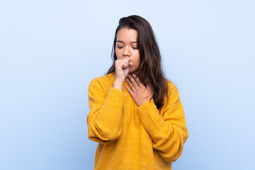 Young Colombian girl with sweater over isolated blue background is suffering with cough and feeling bad