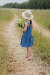Fotobehang 6 years old girl with bouquet of chamomiles looks away towards the horizon © Albert Ziganshin