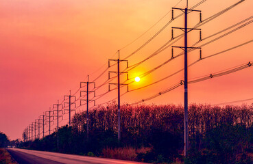 Fototapeta na wymiar Silhouette of electric pole with cable on dramatic sunset sky along the road
