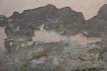 Old dirty weathered wall with layers of plaster falling off ready for repair