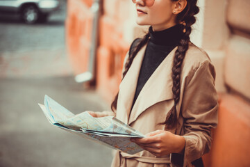 Cropped shot of female wanderer is sightseeing, holding map in hands in a foreign city during...