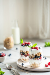 Two glasses of parfait made of granola, berries and yogurt on the table. Shot at angle with place for text, selective focus.