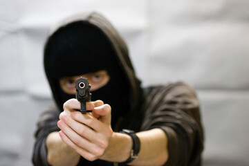 Armed person in a hoodie is pointing a handgun