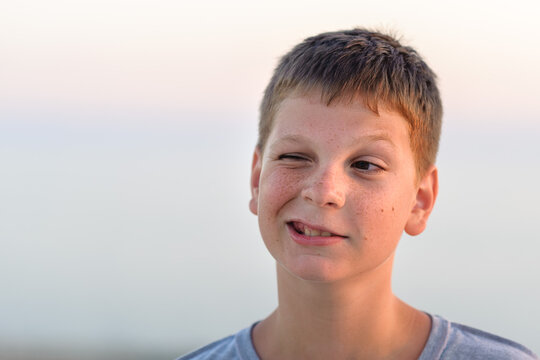 Portrait of a grimacing boy, close-up, tan, evening shot.