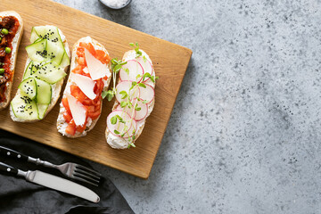 Sandwiches with vegetables, radishes, tomatoes, cucumbers and microgreens on gray. View from above.