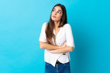 Fototapeta na wymiar Young caucasian woman isolated on blue background making doubts gesture while lifting the shoulders