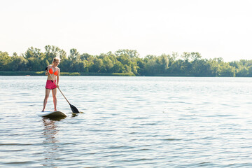 Young attractive woman on stand up paddle board in the lake, SUP