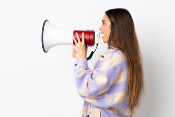 Young caucasian woman isolated on purple background shouting through a megaphone