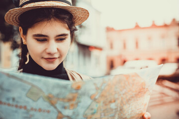 Cropped shot of lady excited about visiting new places, holding a map in hand, weared in trendy hat...