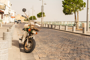 Retro motorbike, moped on the narrow street on the promenade of a small tropical village.