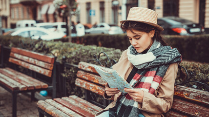 Shot of a a female tourist sitting on a bench, looking at road-map for place she wants to visit.