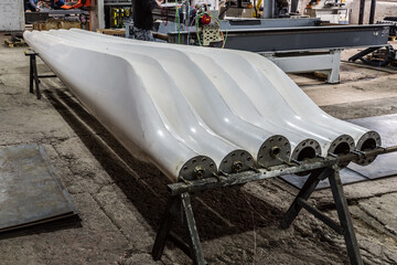 Two sets of freshly made blades for wind turbines in a factory floor. The picture was taken in Russia, in the Orenburg region, in the production room of an industrial enterprise
