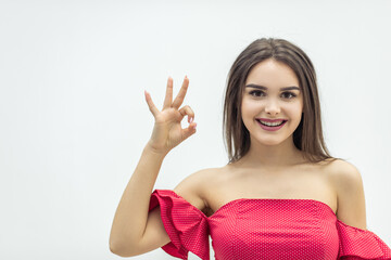 Close up image of lovely girl showing ok sign and smiling over white background.