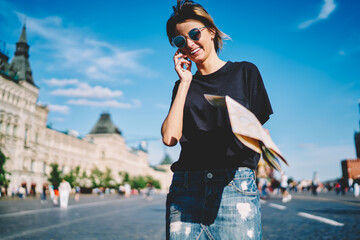 Attractive prosperous hipster girl in stylish sunglasses sincerely laughing while contacting with...