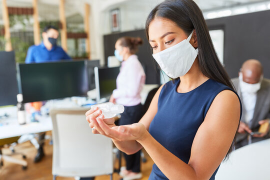 Woman Using Face Mask In Office While Disinfecting Hands