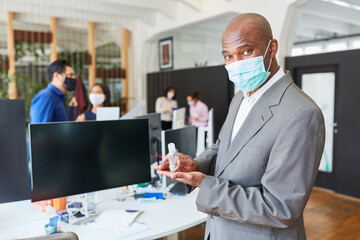 Businessman wearing face mask while disinfecting hands