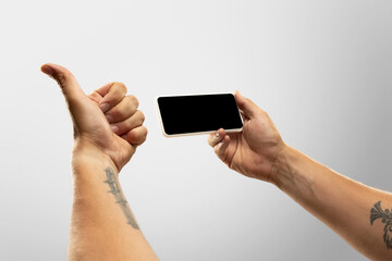 Exciting moments. Close up male hands holding phone with blank screen during online watching of popular sport matches, championships. Copyspace for ad. Devices, gadgets, technologies concept.