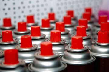 aerosol cans with a bright red lid are in a row. Macro photo. Selective focus on the nozzle. paint