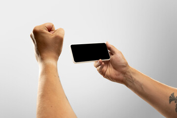 Exciting moments. Close up male hands holding phone with blank screen during online watching of popular sport matches, championships. Copyspace for ad. Devices, gadgets, technologies concept.