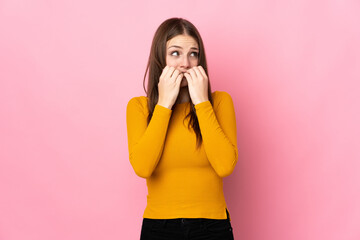 Young caucasian woman isolated on pink background nervous and scared putting hands to mouth