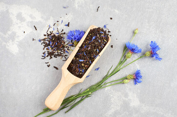 Blend of black tea, cornflowers petals and thyme in wooden scoop with fresh blue cornflowers