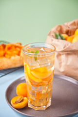 Summer cold drinks homemade apricot lemonade ice tea with ice cubes and mint