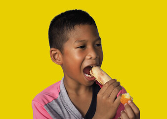 The boy eats hot dog Happily Isolated on a yellow background. Embed clipping path. Junk food concept.