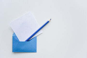 selective focus, white paper sheet and blue pencil out of the blue envelope