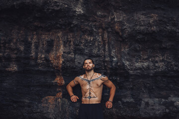European man with drawings on his body walks among the rocks