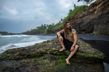European man with drawings on his body walks among the rocks
